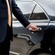 A driver is ready to open the door to a luxury sedan for the passengers